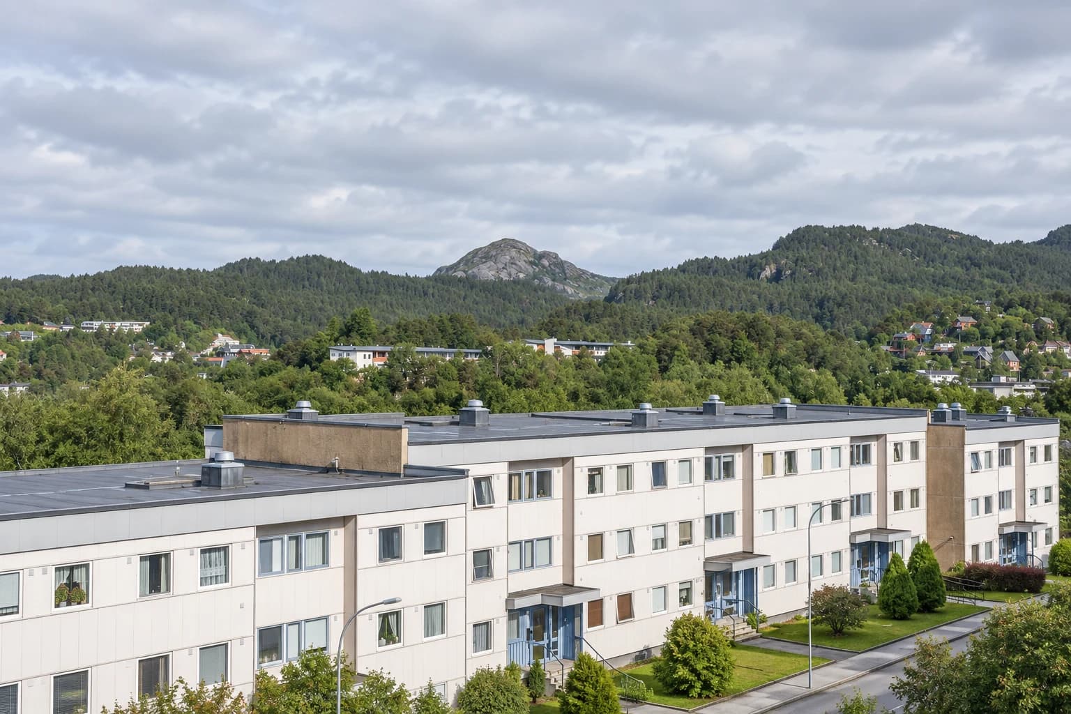 AI-illustrasjon inspirert av Fyllingsdalens lavblokker med flate tak, grøntdrag og skogkledde åser.